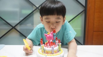 어린-아이가-생일-축하케이크-불을-끄고있는-모습