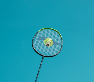 배드민턴 라켓위에 얹혀있는 셔틀콕, 그 위 하늘이 비춘다.