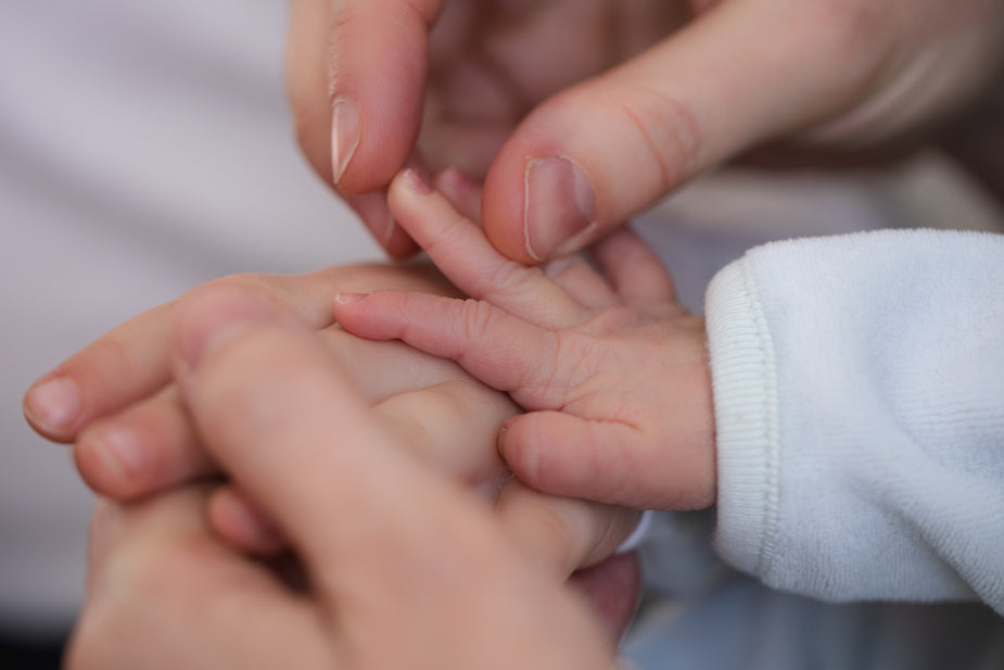 parent holding baby's hand