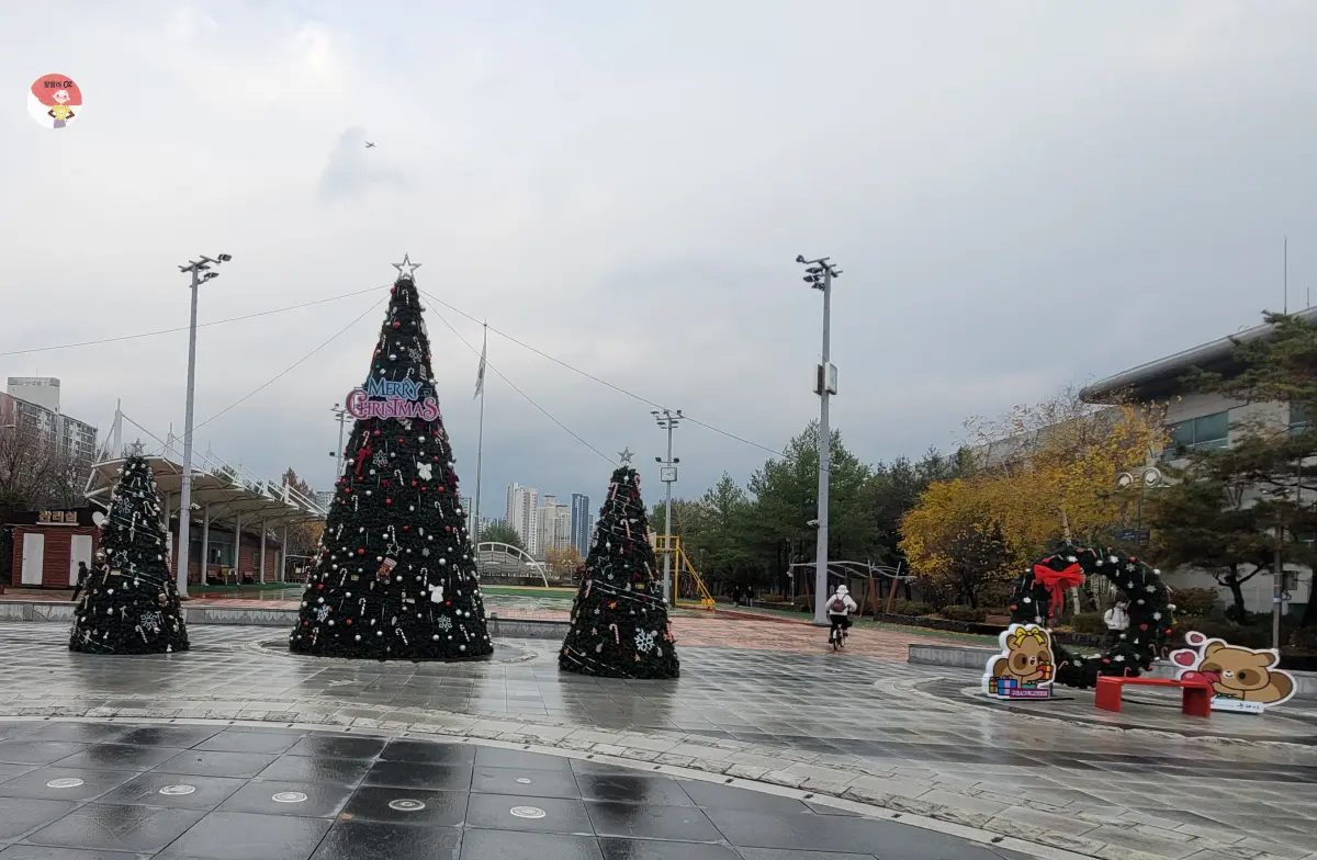 우리동네 야외 공간에 꾸며진 크리스마스 장식이, 큰 트리들과 귀여운 캐릭터들이 있는 아기자기 소박한 축제 분위기
