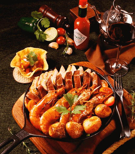 둥그런 프라이팬에 통새우와 통감자, 오리로스구이가 가득하다. 주변엔 붉은 와인이 담긴 투명한 유리잔이 있다.