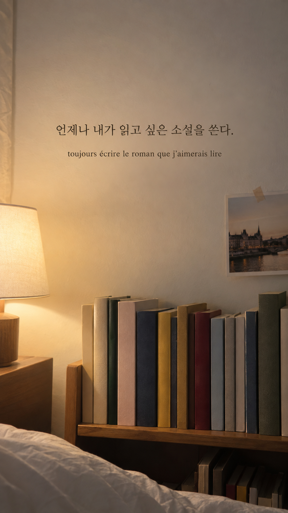 조명 옆 작은 책장 배경에 담은 기욤 뮈소의 말: 언제나 내가 읽고 싶은 소설을 쓴다.