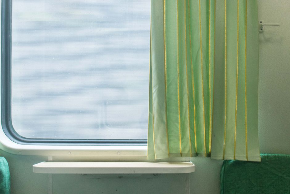 Green curtain beside a train window, showcasing interior design on public transport.