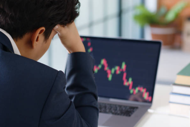 불경기를 나타내는 노트북 화면과 고민하는 회사원 사진