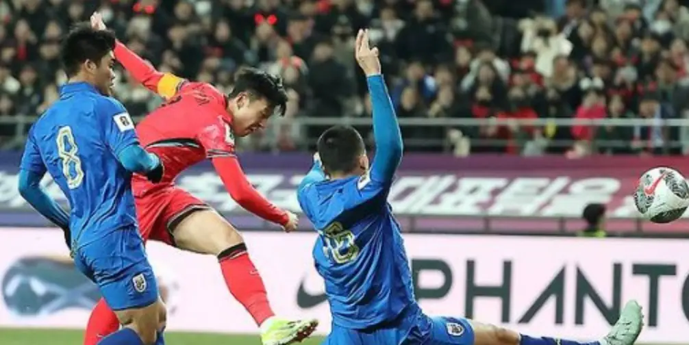 태국전- 붉은 유니폼을 입은 손흥민이 공을 힘껏차고 그 주위로 태국선수 2명이 막고있는 모습