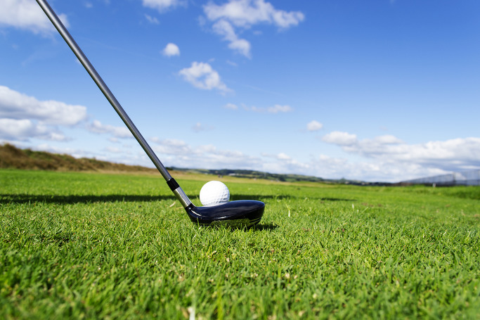 하늘아래 골프채가 골프공을 치려는 모습