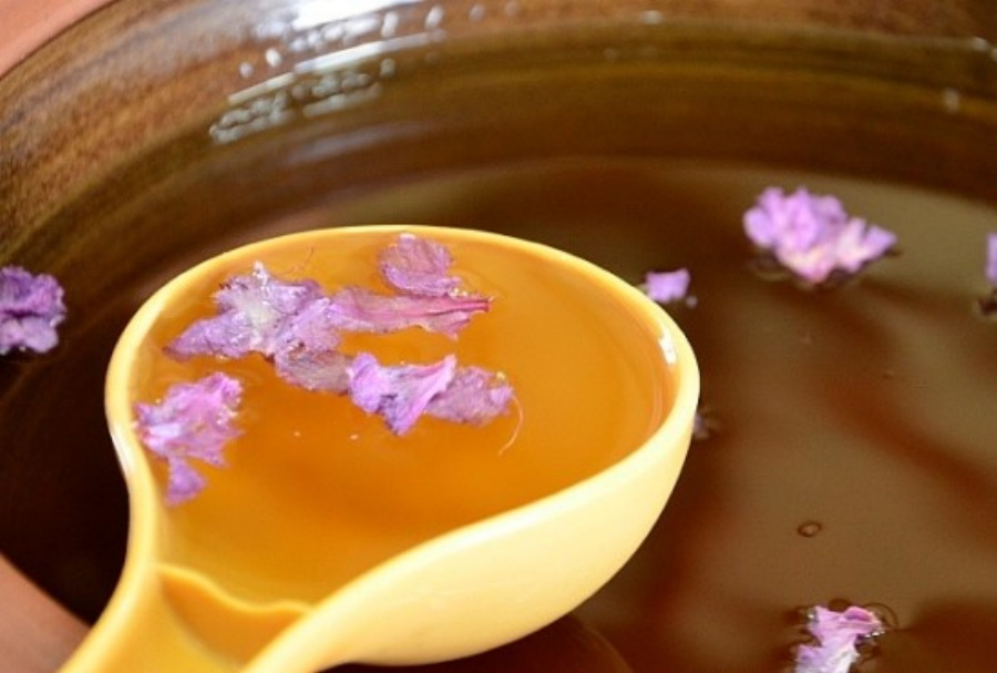 진달래꽃을 같이 넣어서 숙성을 시킨 두견주를 담은 고동색 술독에 동그란 플라스틱 국자로 술을 가득 퍼 담은 것을 술독에 걸쳐놓고 찍은 사진