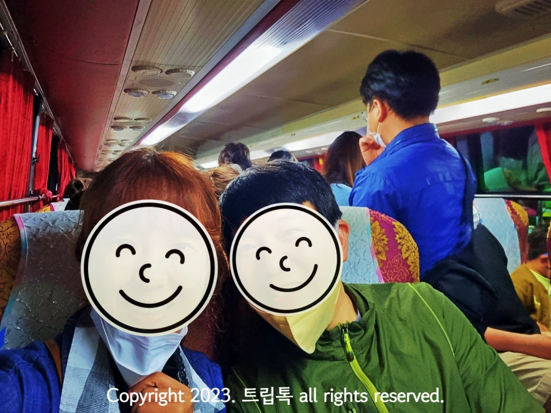 버스 안에서 의자에 나란히 앉은 두 사람이 사진을 찍고 있다.