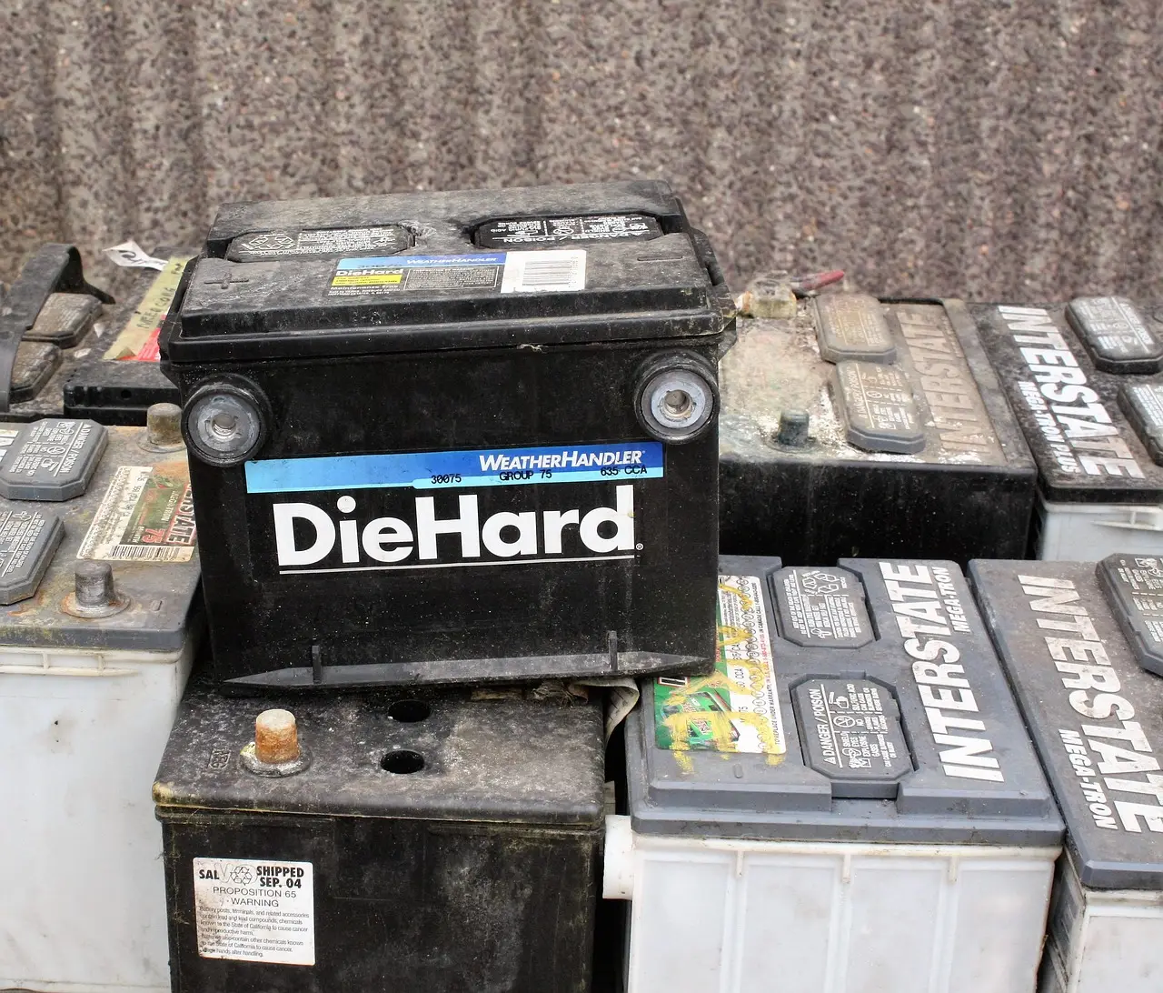 배터리- 먼지쌓인 배터리가 놓여있는 모습 맨 위 검정색 자동차용 대형 배터리