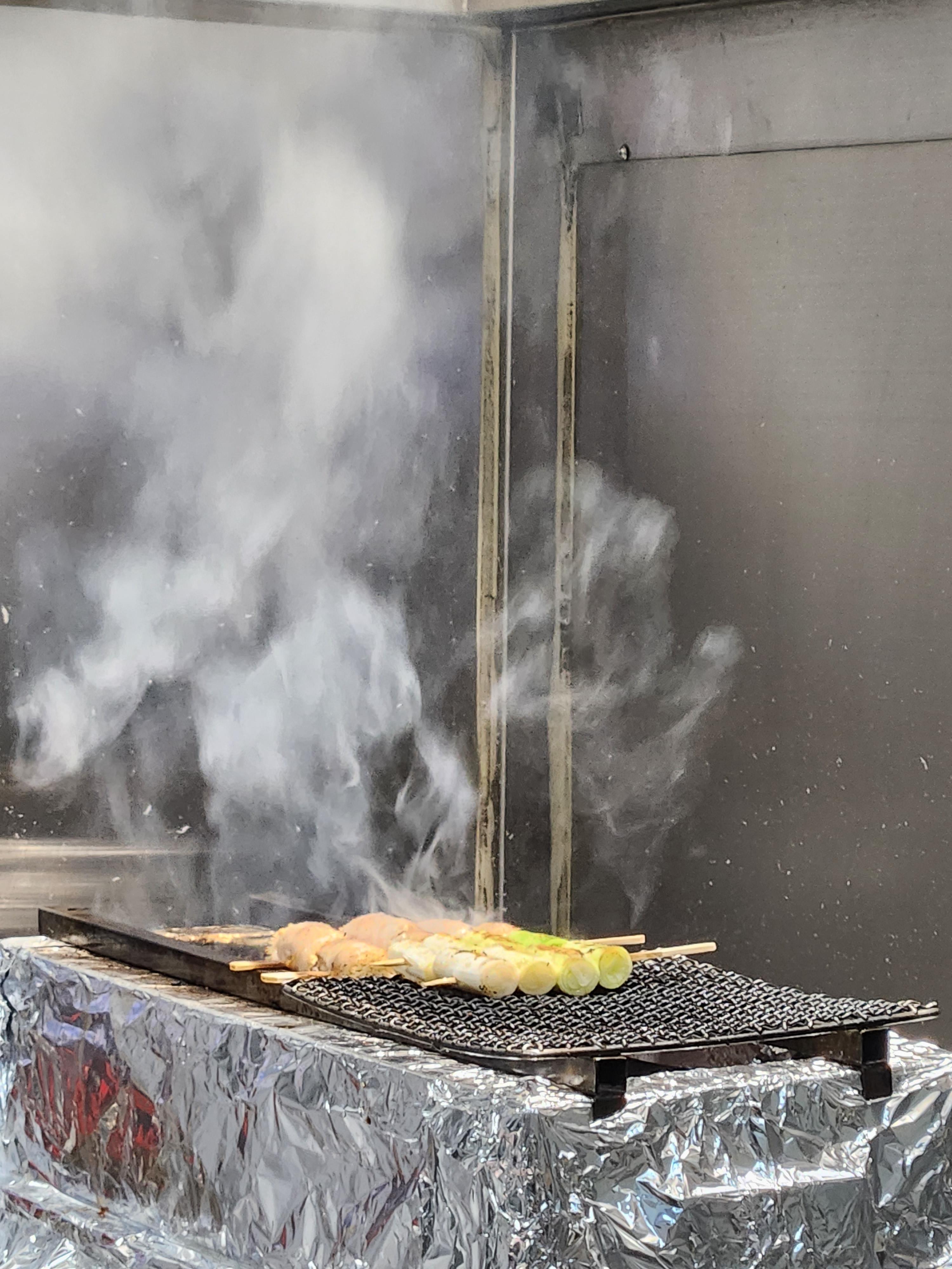 닭고기와 채소가 숯불 위에서 구워지는 장면, 연기 가득한 현장감