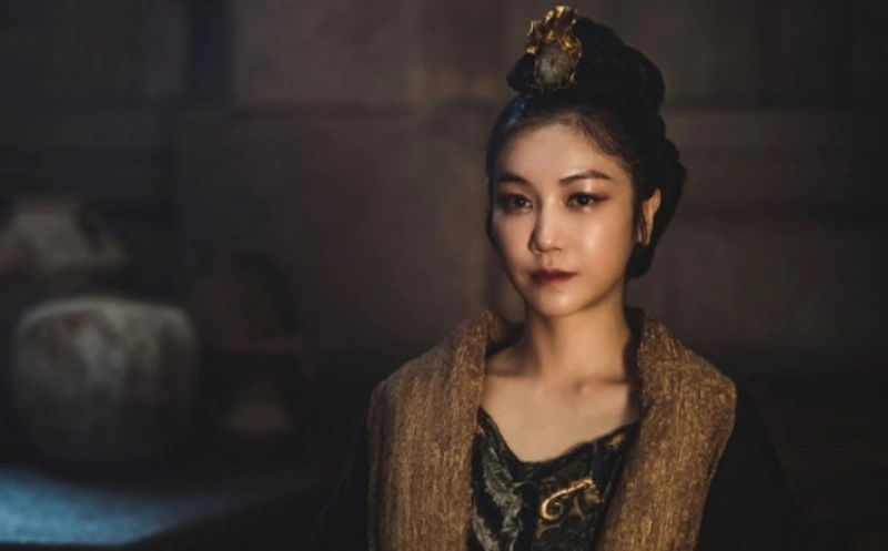 갈색과 검은색이 섞인 우아한 드레스에 머리엔 금색 장신구로 머리를 말아 올린 아라문의 검 태알하 캐릭터