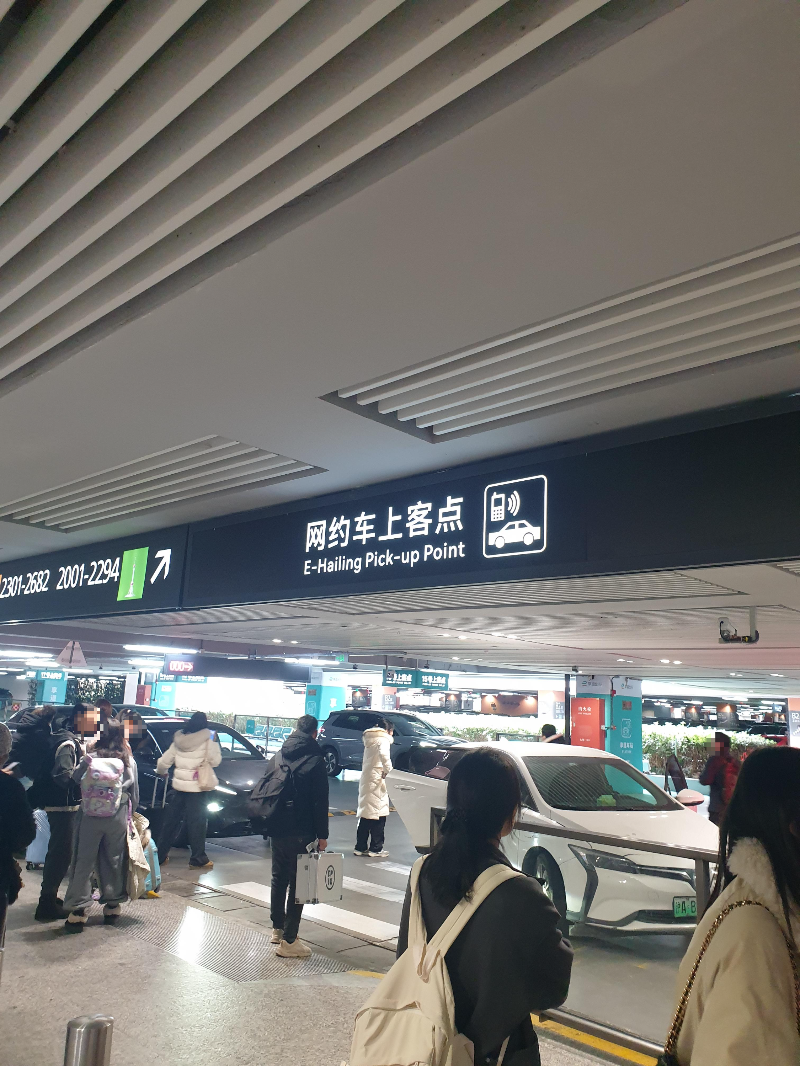 DiDi 차량을 기다리는 많은 고객들. 위에 안내 표지판이 있다.