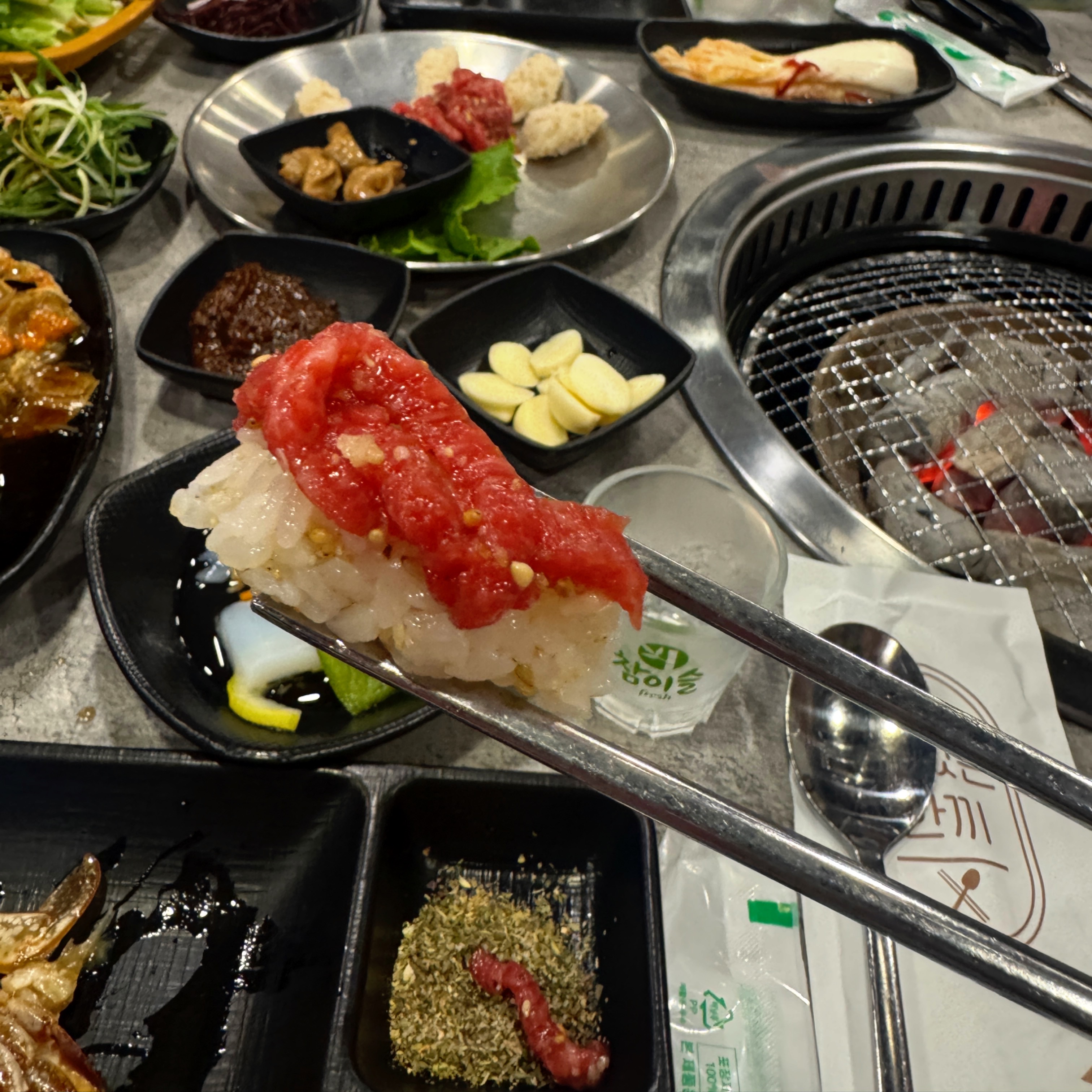 삼거리 명품한우에서 육회초밥을 젓가락으로 집은 클로즈업 장면. 붉은 육회와 윤기 도는 밥알이 조화를 이루고 있다.