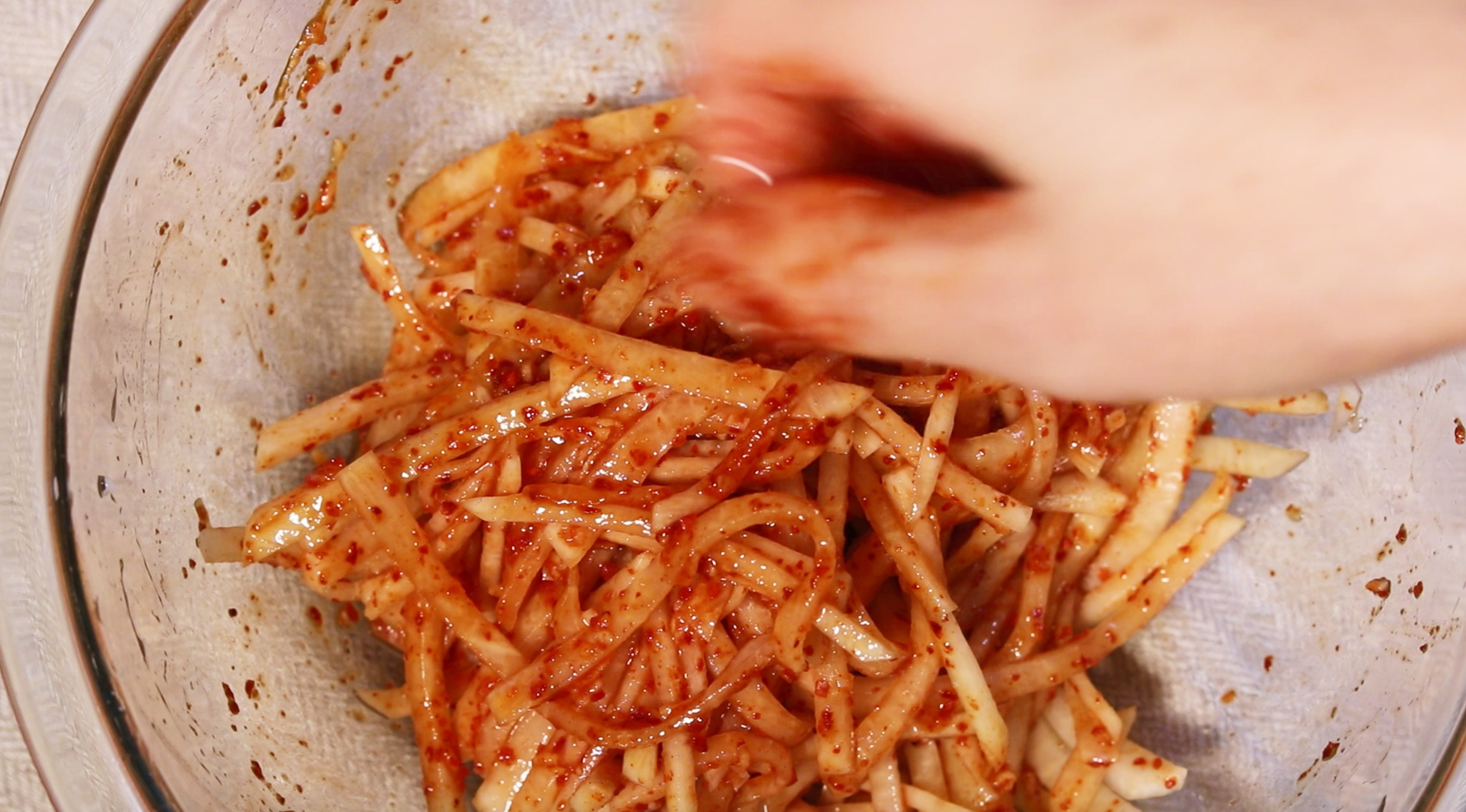 손으로 무와 양념장을 살살 뒤적여주며 섞어준다