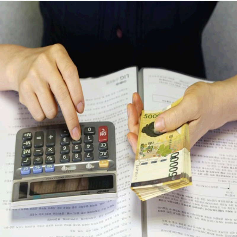 계산기를 두드리며 한 손에 오만 원권 현금을 들고 있는 모습