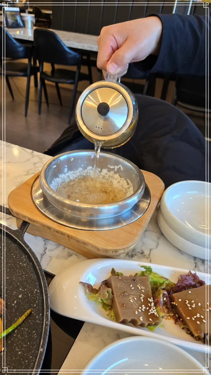 기장-삼삼오오-솥밥에-밥을-퍼낸뒤-남은-누룽지에-따뜻한-물을-붓는-손-장면-근접촬영