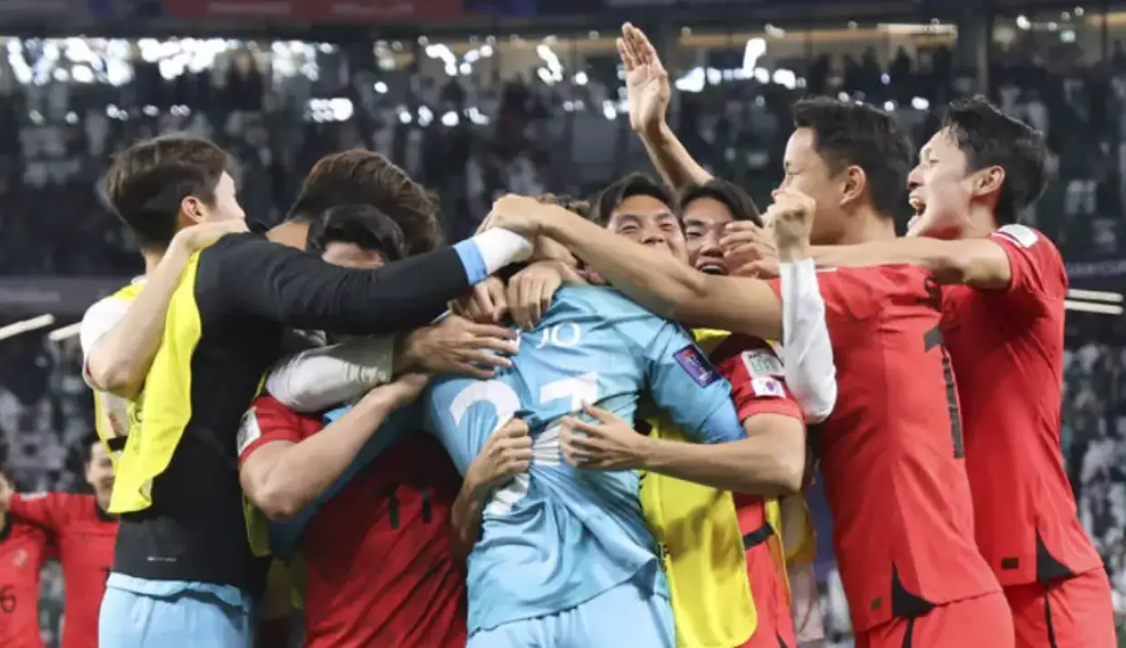 하늘색 유니폼을 입은 선수를 붉은 유니폼 입은 선수들이 안아주는 모습