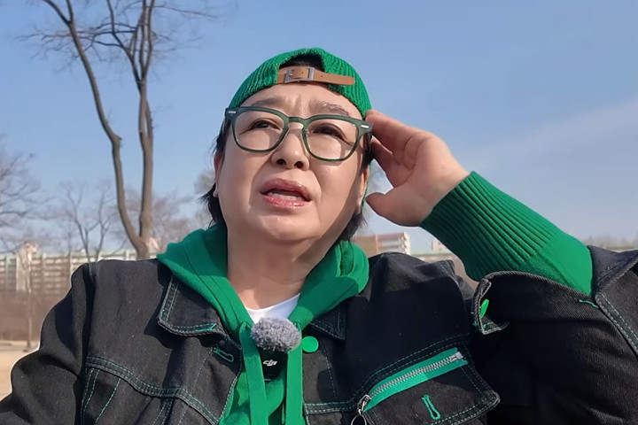 혜은이가 초록색 모자를 쓰고 야외에서 안경을 만지는 모습