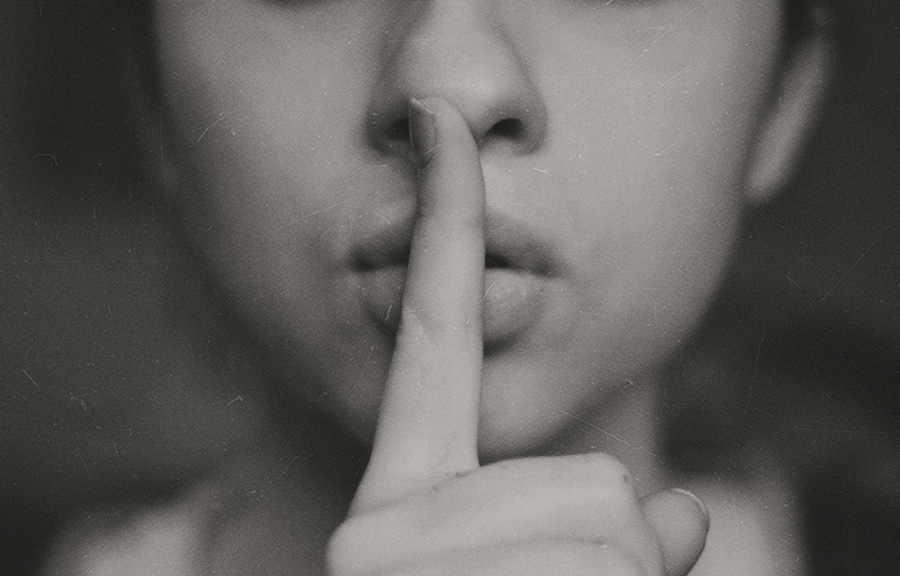한 젊은 여성이 오른쪽 검지손가락을 펴서 본인의 입에 대고 조용히 하라는 것을 표현하고 있는 것을 찍은 사진