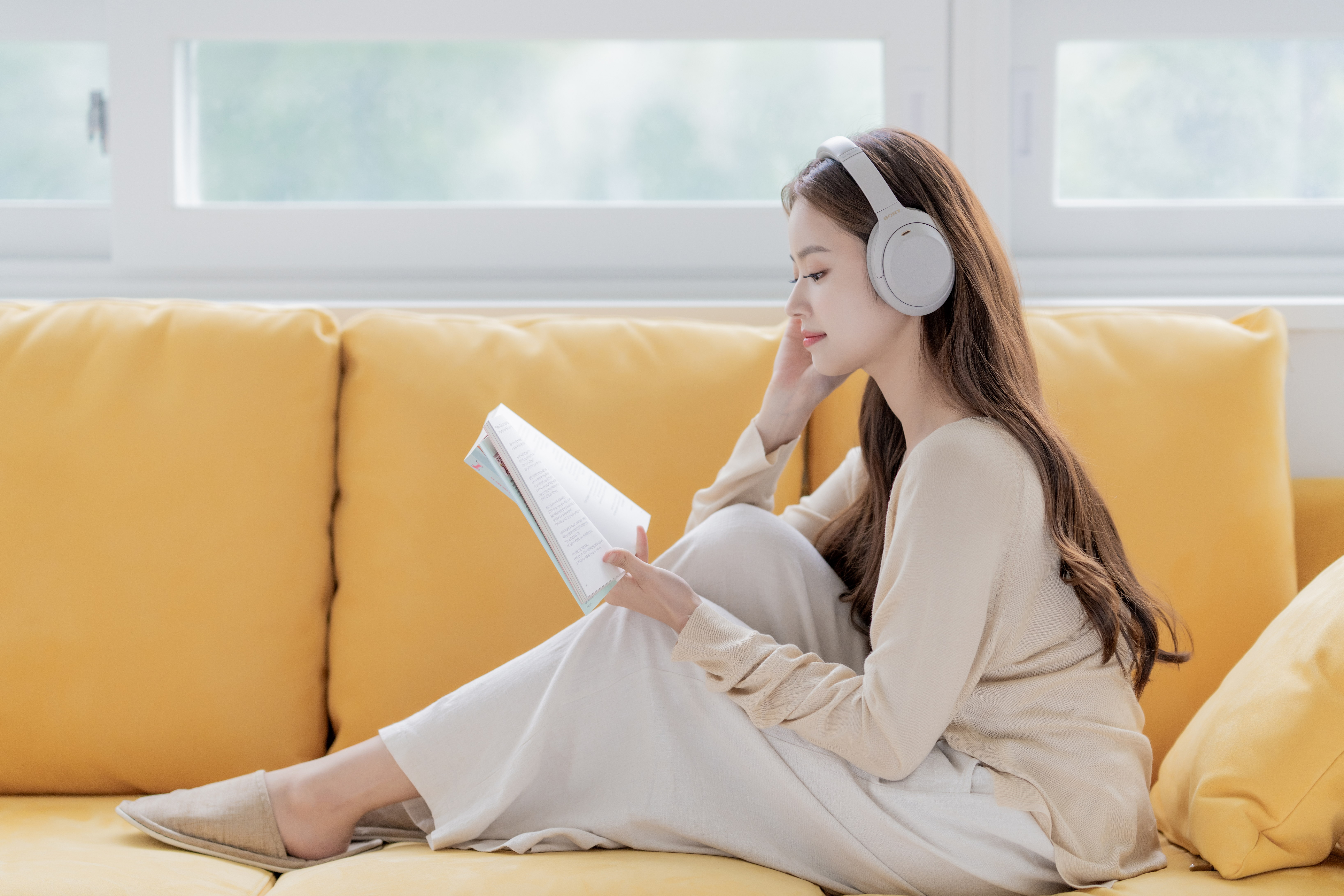소니 헤드폰으로 음악을 들으며 독서를 하는 여자 모습