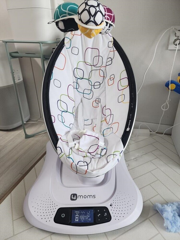 화이트 색상에 아기가 누울수 있는 바운서 입니다 상부에는 공모양의 모빌 3개가 달려있습니다.