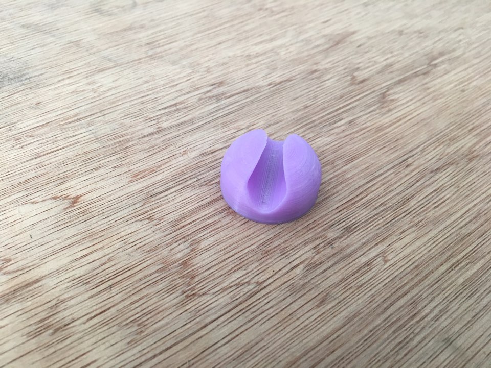 나무 바닥 위에 놓인 3D 프린팅된 보라색 케이블 클립