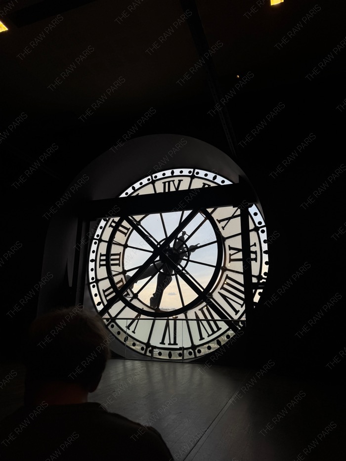 A silhouette of a person looking through the iconic giant glass clock of Musee d'Orsay in Paris⁠