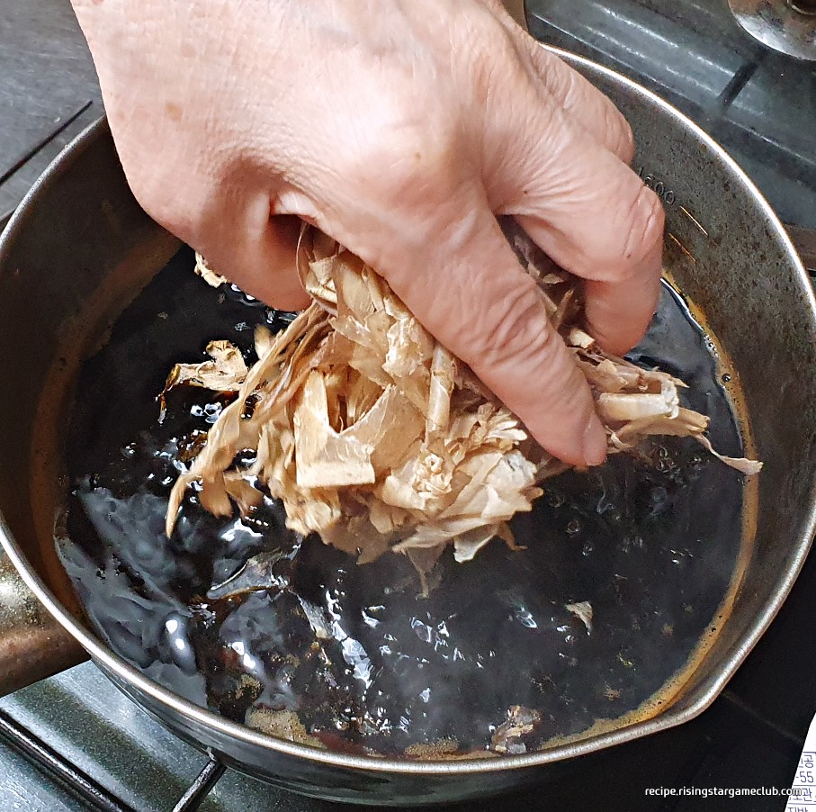 끓고 있는 판모밀국수의 육수(쯔유)에 가다랑어포(가쓰오부시)를 넣는 사진