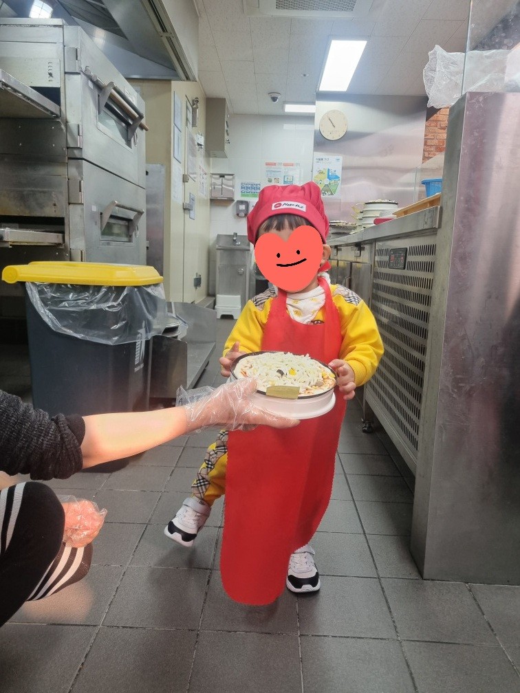 주방에서 피자를 들고 있는 아이