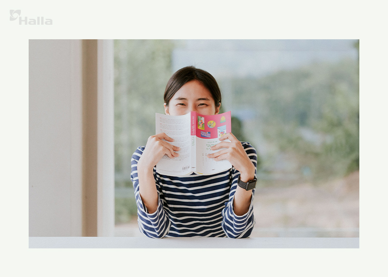 책으로 얼굴을 가린 채 웃음 짓는 강하늘 연구원 이미지