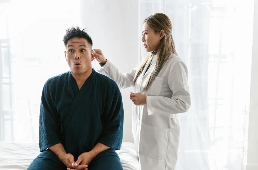 한 남성이 귀쪽의 검진을 받고 있다.