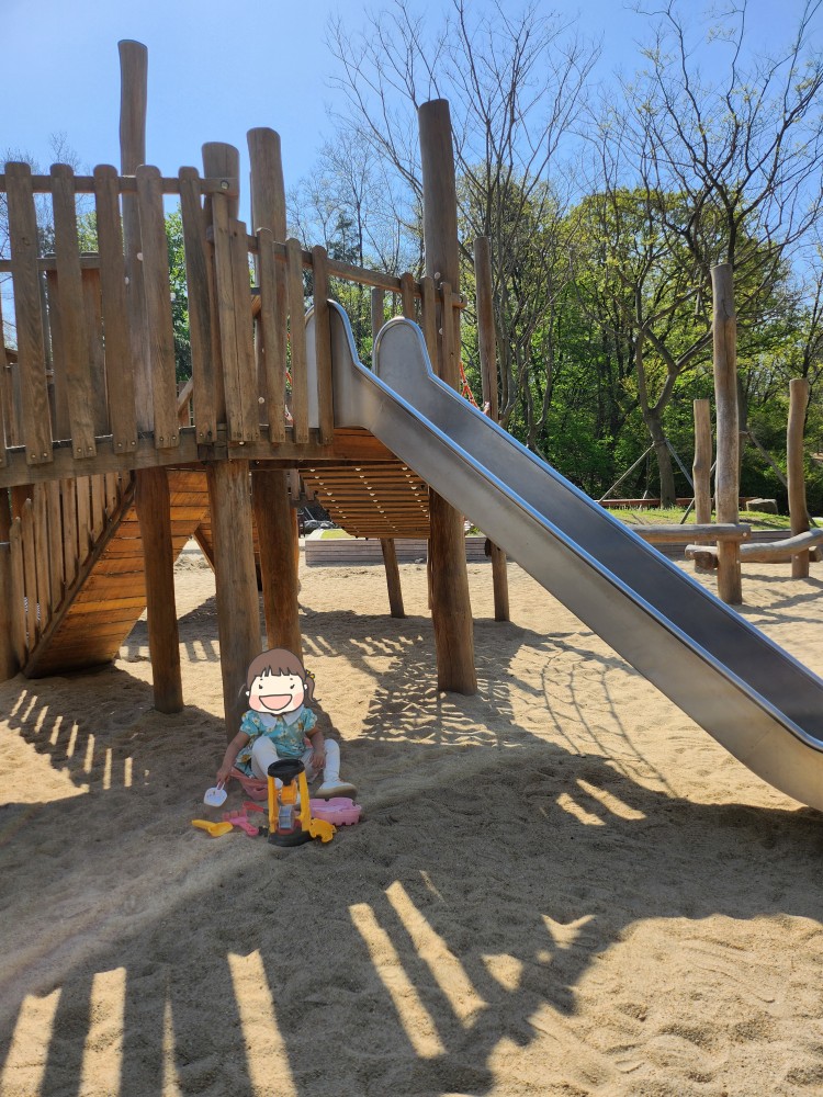 미끄럼틀 아래에서 모래놀이를 하는 아이