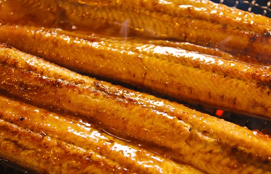 철판에 노릇하게 구어진 장어구이가 4개 있다. 장어구이는 길쭉하고 익힌 살은 노릇노릇하다.