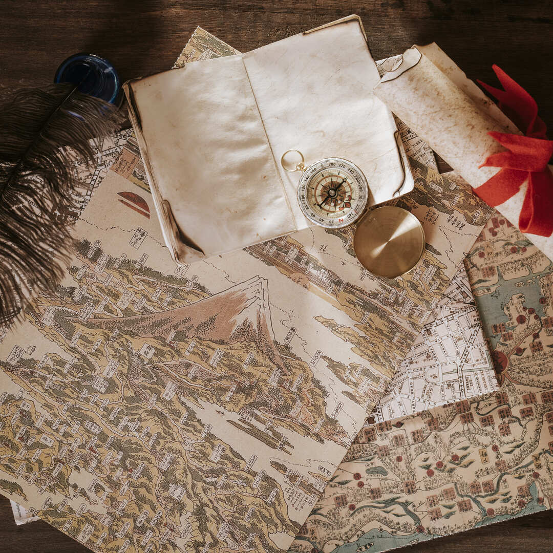 나침반, 지도, 잉크로 쓴 연대기, 손때 묻은 지도가 그려진 사진.