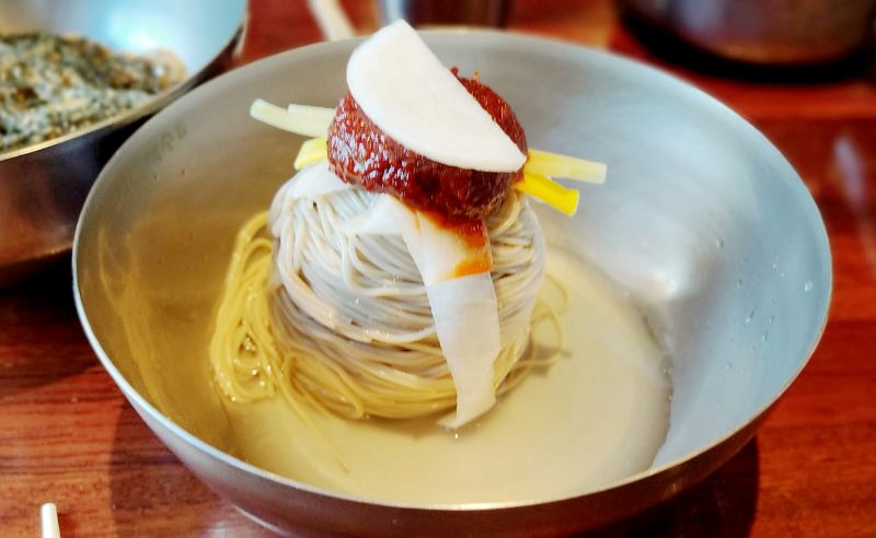 비빔막국수 메밀면위 양념 자작한국물 고명이 올려져있다