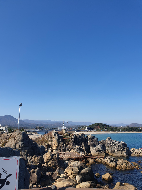 파란 하늘 아래 파란 바다와 회색의 돌산이 보인다.