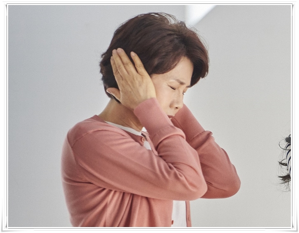 손바닥으로 양쪽 귀를 막고 두 눈을 감은 채 다소 힘겨운 표정을 짓고 있는 중년 여성의 옆모습