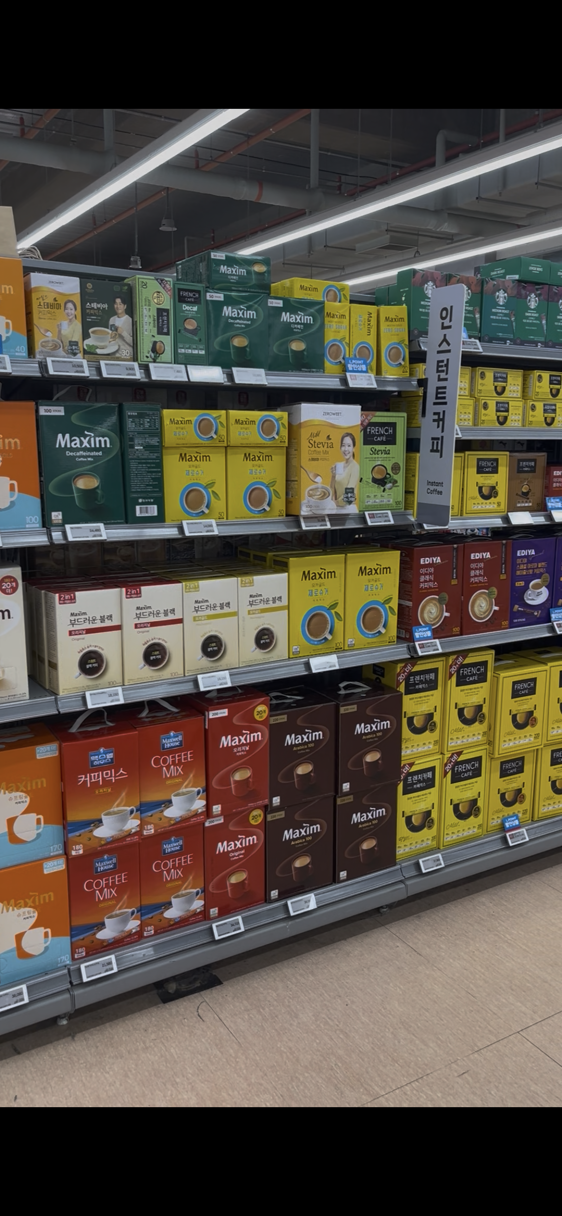 A supermarket shelf in Korea displaying various brands of instant mix coffee, including Maxim and French Caf&eacute; &mdash; showing how mix coffee remains a staple in Korean daily life.