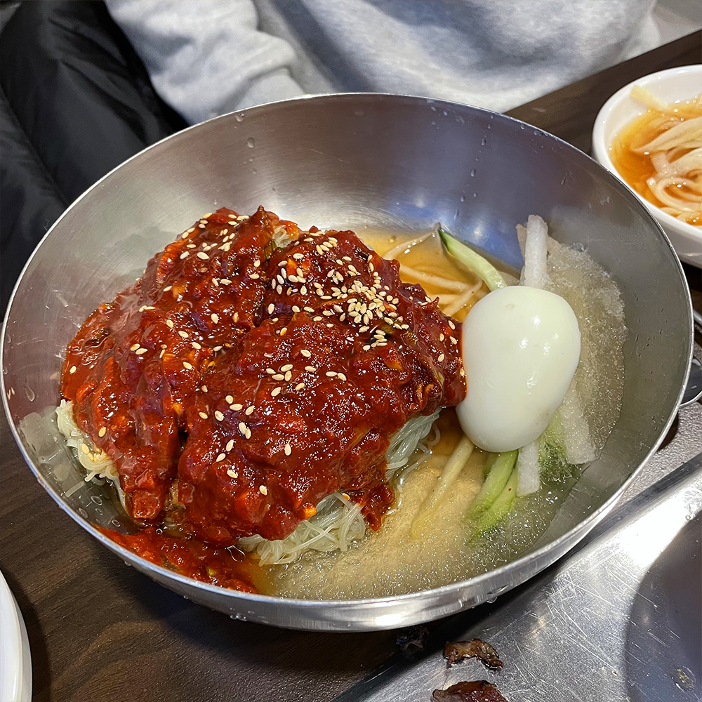 달걀과-비빔냉면이-담긴-스테인리스-그릇이-있습니다.