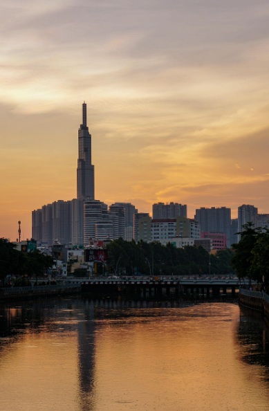 황금빛 노을이 지는 사이공강 너머로 보이는 베트남 호치민의 가장 높은 마천루 랜드마크 81과 현대적인 도심 스카이라인 전경