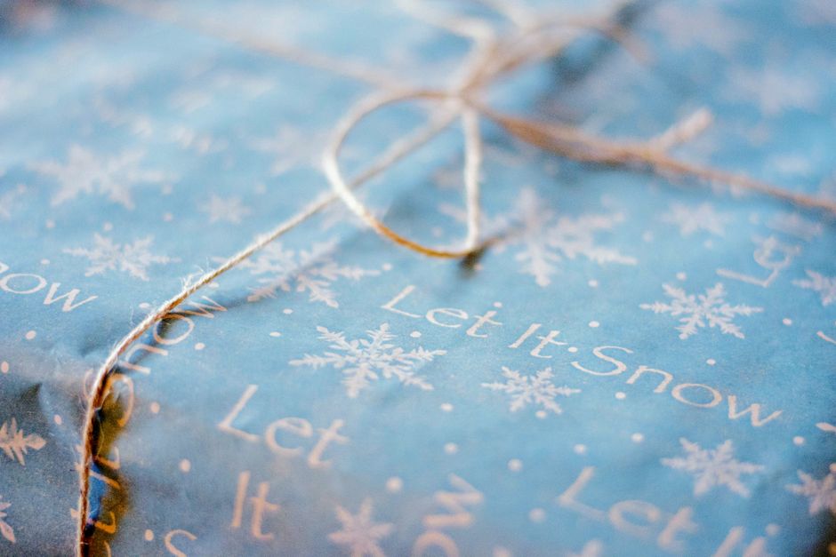 Close-up of a gift wrapped in blue snowflake-themed paper with 'Let It Snow' text, perfect for winter holidays.