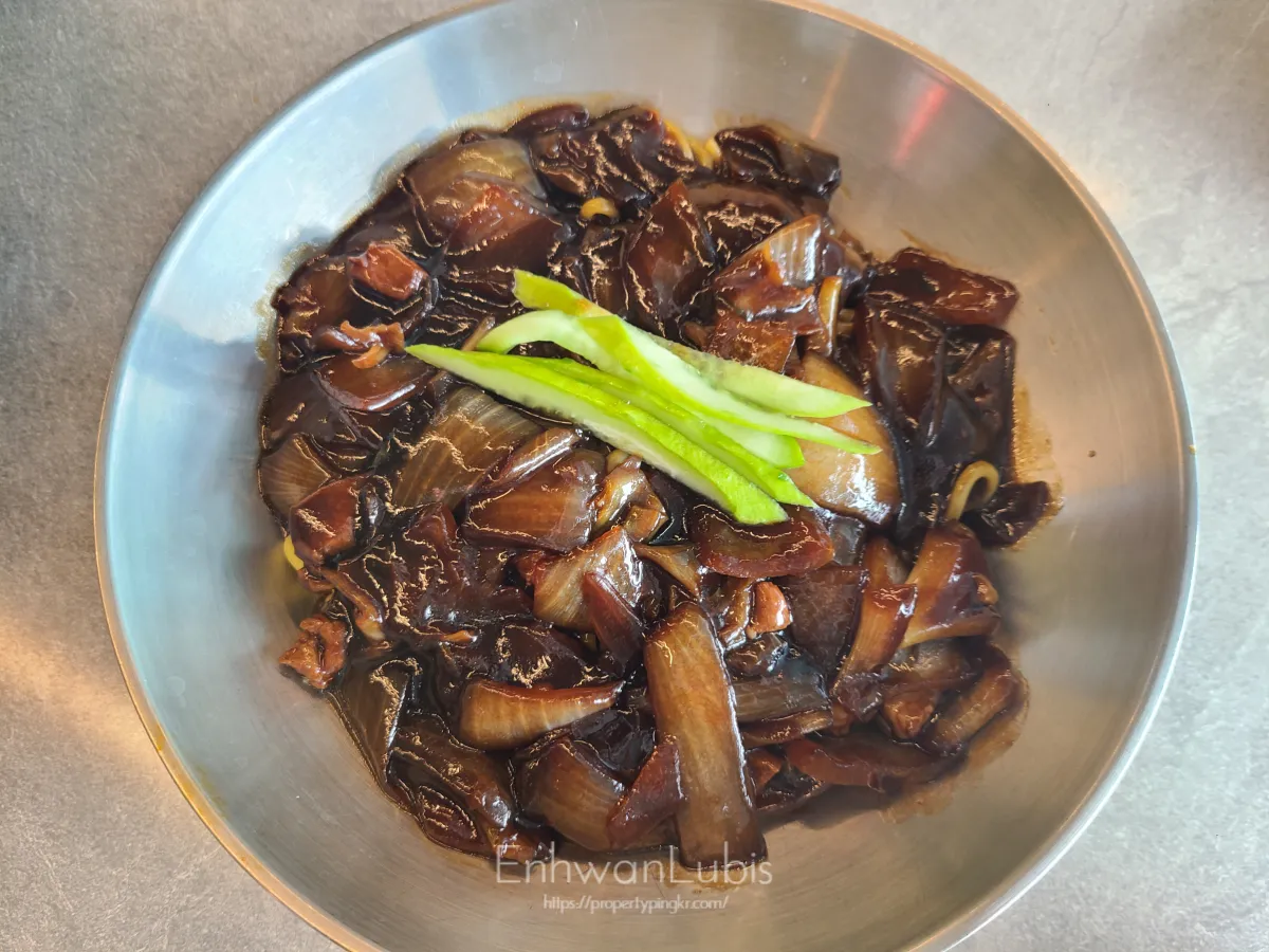 스텐-그릇에-담겨진-짜장면-양파와-고기-제일-위에-채썬-오이가-올려진