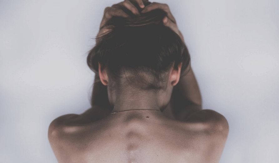 카페인 과다 섭취 증상으로 두통으로 두 손을 머리에 감싸고 있는 여성