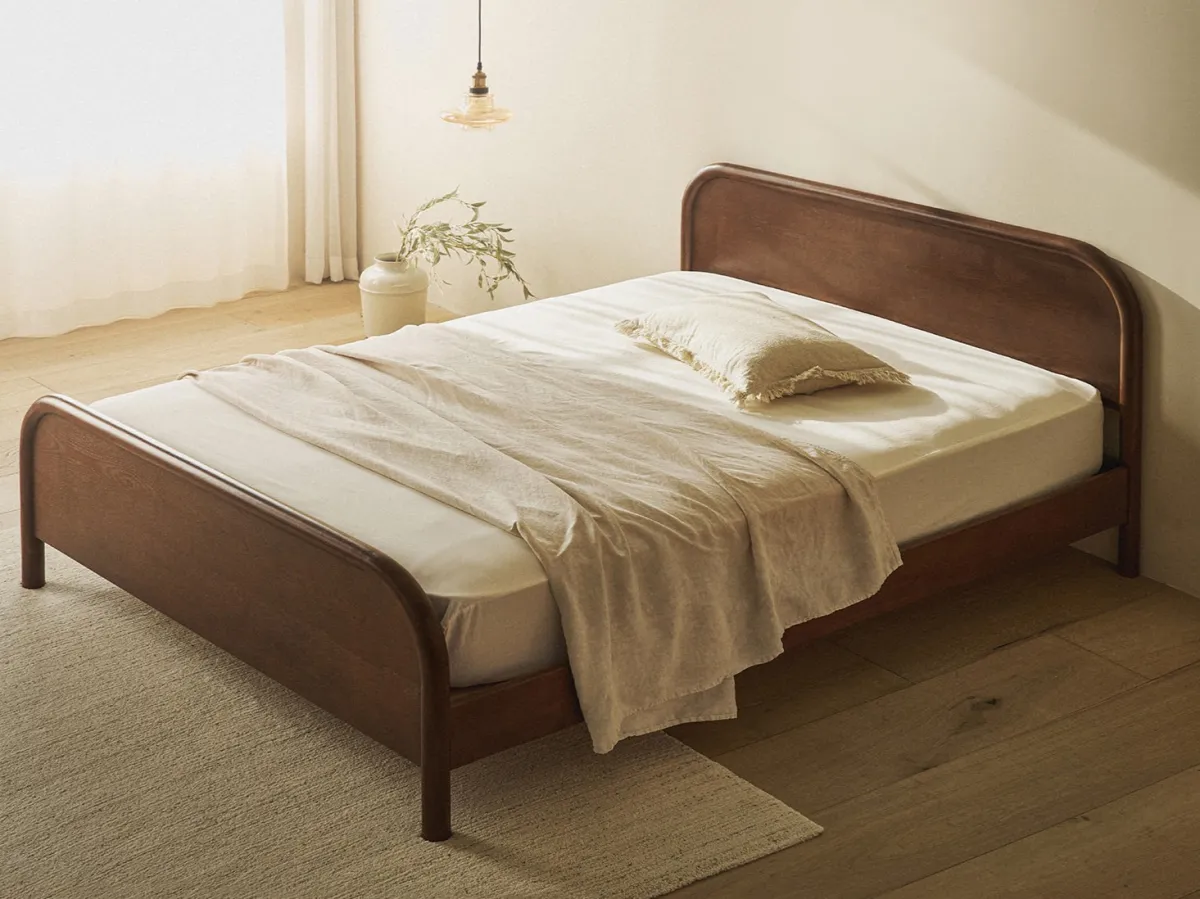 아이보리색-따뜻한-느낌의-방에-월넛-색상의-침대-동그란-모양의 헤드와풋보드