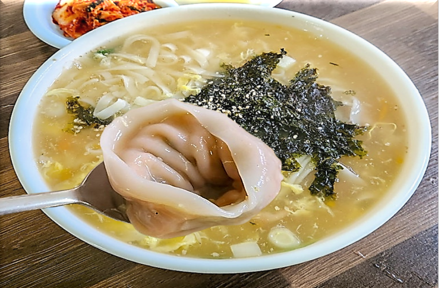 투명한 육수에 달걀이 풀어진 심플한 고명의 담백한 흰칼만두국