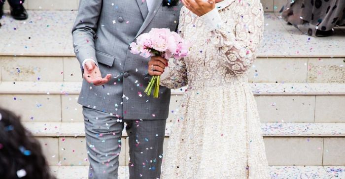 결혼식 후 계단 위에서 꽃잎을 맞고 있는 신랑 신부의 모습. 혼례비 지원 항목을 상징하는 이미지