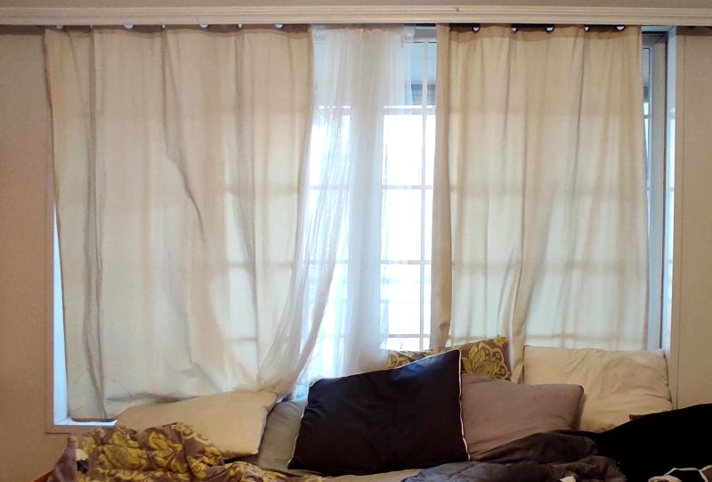 단창으로 이루어진 샷시 앞에 침대를 두어 추워서 커튼으로 막아둔사진