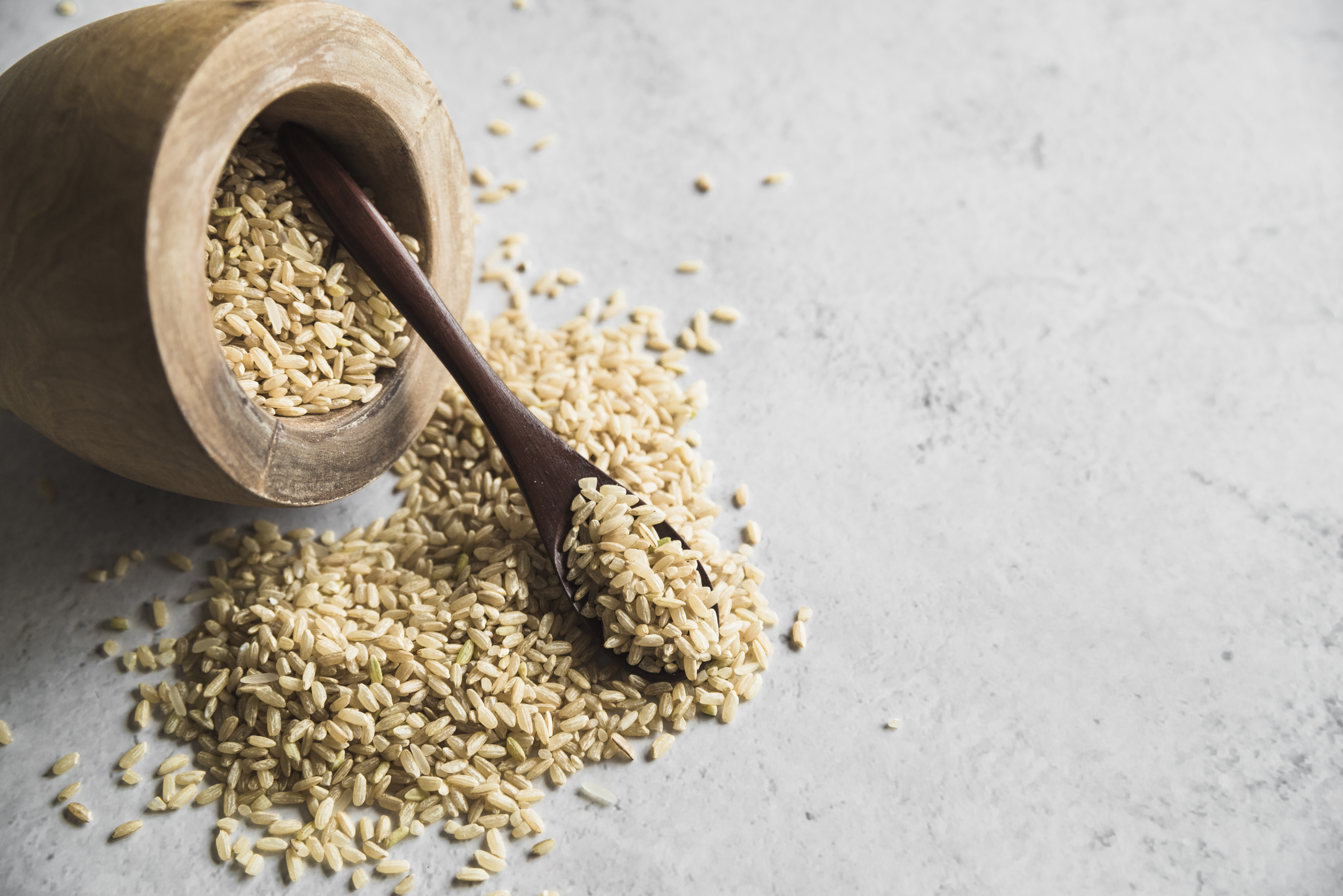 나무 그릇에 가득 담아져 있던 현미를, 그릇을 쓰러뜨려서 바닥에 반 정도 쏟아 놓고, 현미를 가득 담은 숟가락을 기대놓은 사진