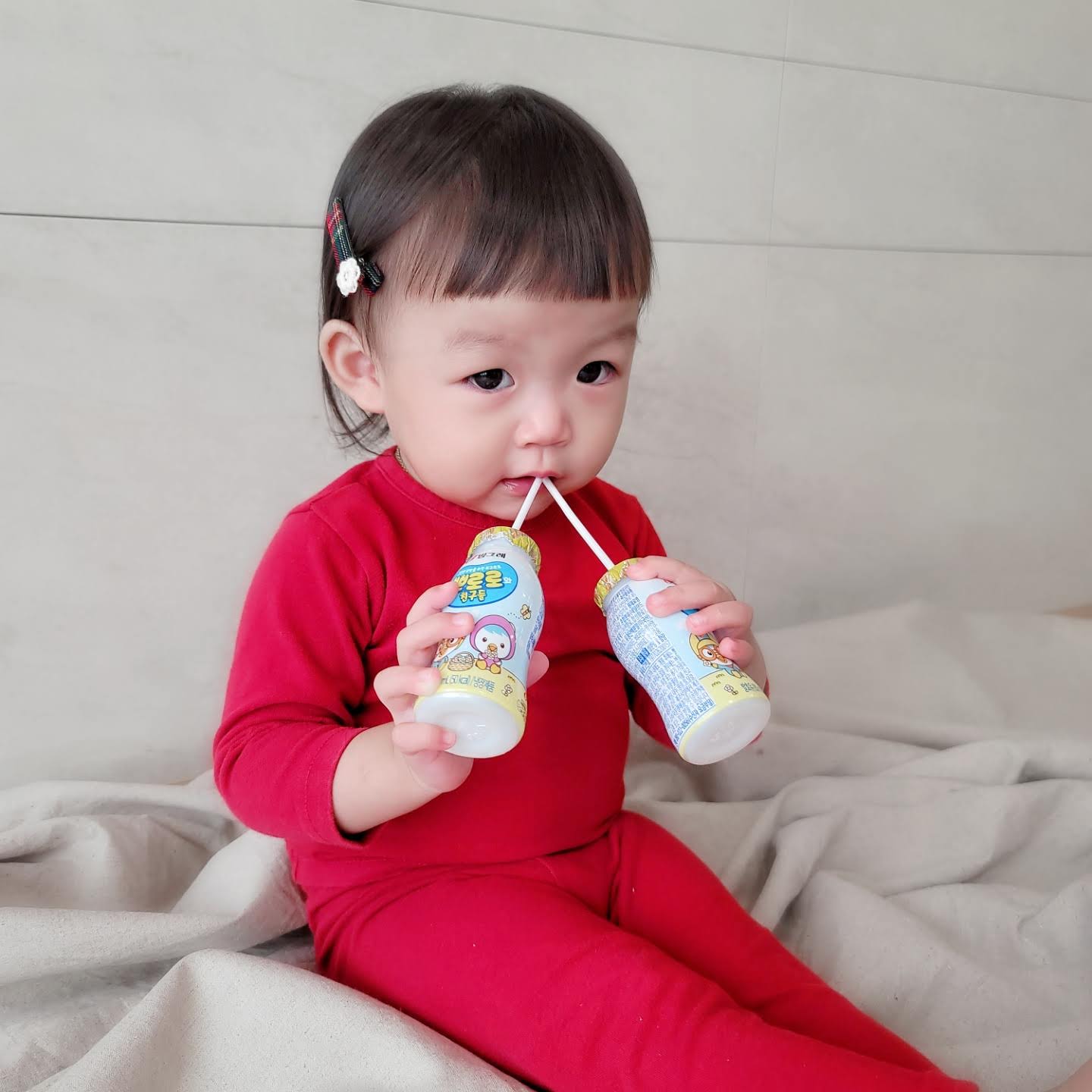 요구르트 먹으며 카메라 응시하는 아기