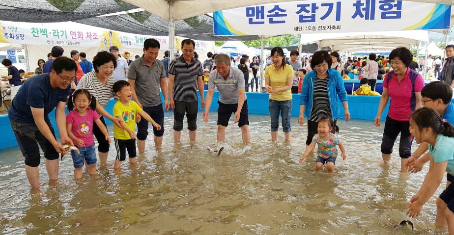 수조 안에서 수산물 맨손잡기 체험을 하며 즐거워하는 가족